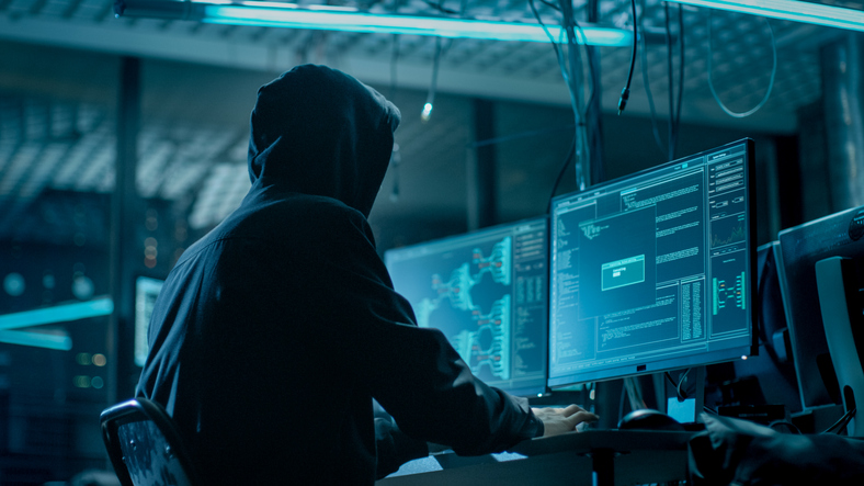 Shot from the Back to Hooded Hacker Breaking into Corporate Data Servers