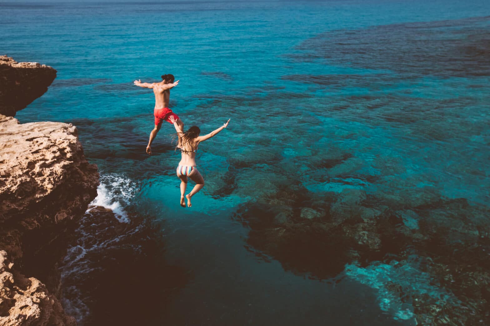 man and women jumping into the sea
